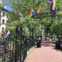 An image of the Stonewall National Monument, a metal arch with rainbow pride flags hanging from it.