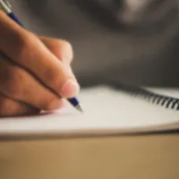 Picture of hand writing in a notebook.