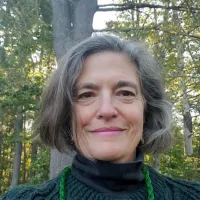 a photograph of guest storytime reader Dayna Langfan, Caucasian, short to medium gray hair in wooded background