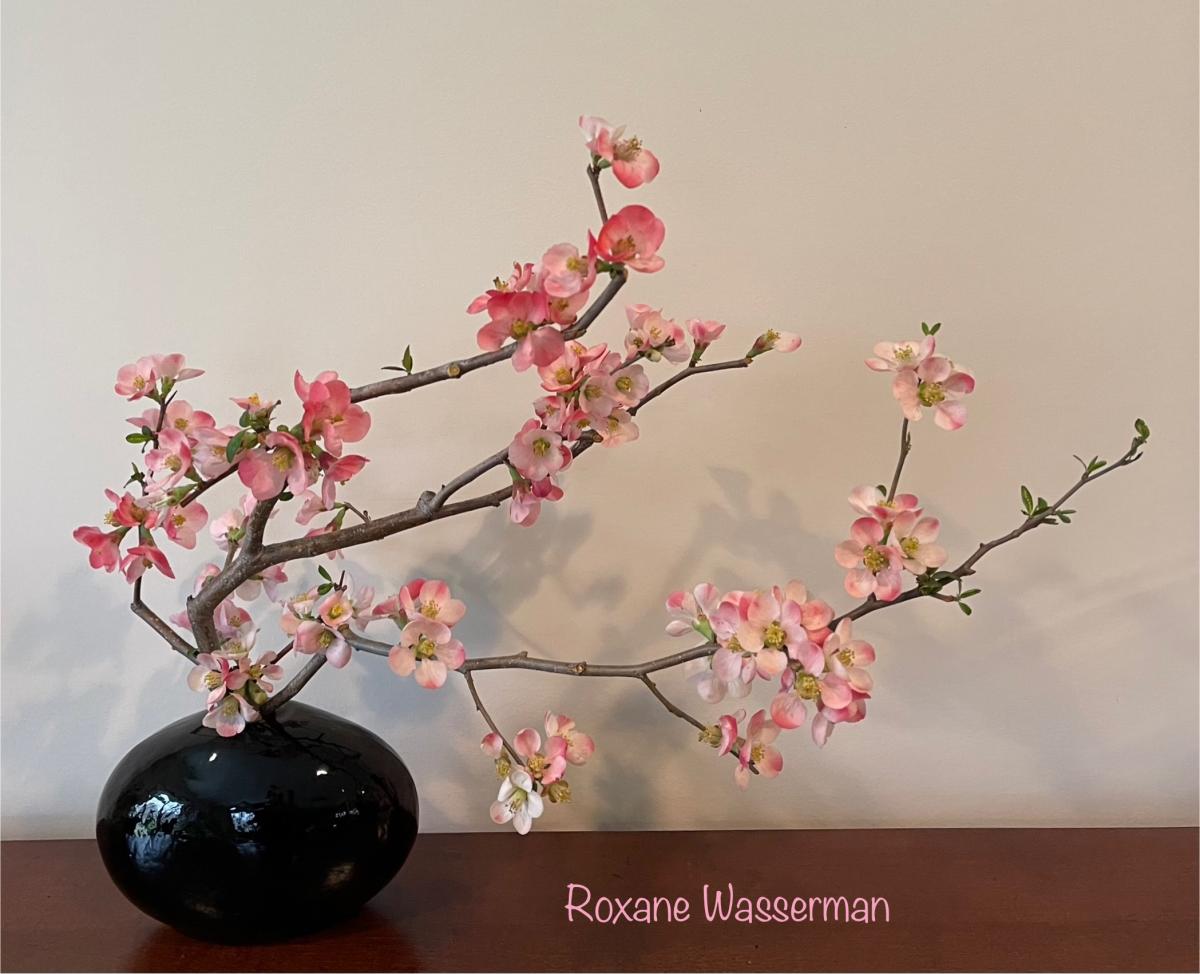 Ikebana flower arrangement - pink flowers in black vase on a table 
