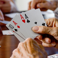 adult hands holding playing cards at a table